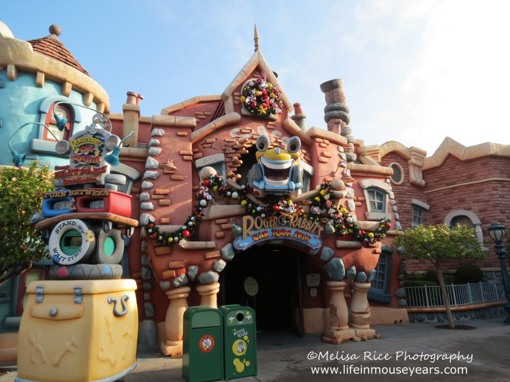 The entrance to Roger Rabbits Cartoon Spin. Brick style building with a yellow cartoon cab coming out of the building above the entrance.
