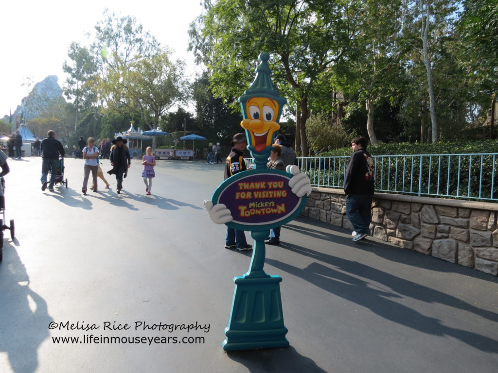 A cartoon lamp post holding a sign that says thank you for visiting Mickey's Toontown.