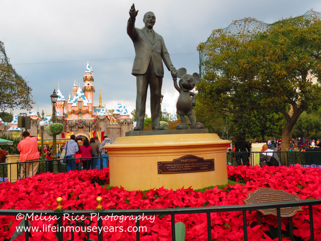 Partners statue in Disneyland from December with poinsettias surrounding the base.