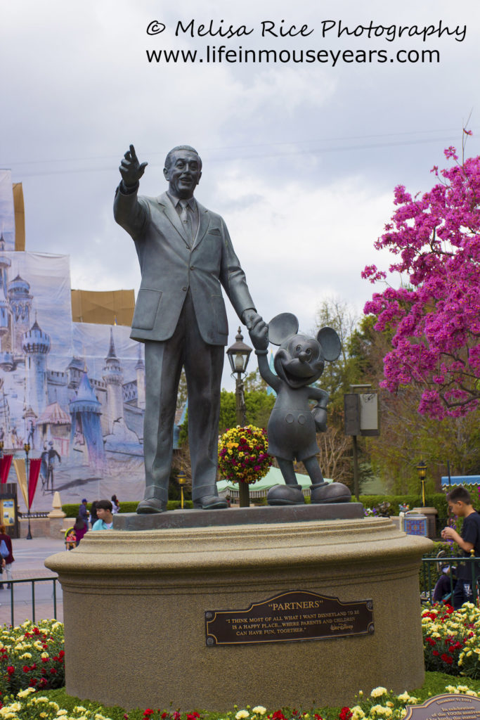 Partners statue with red and yellow flowers around the statue.